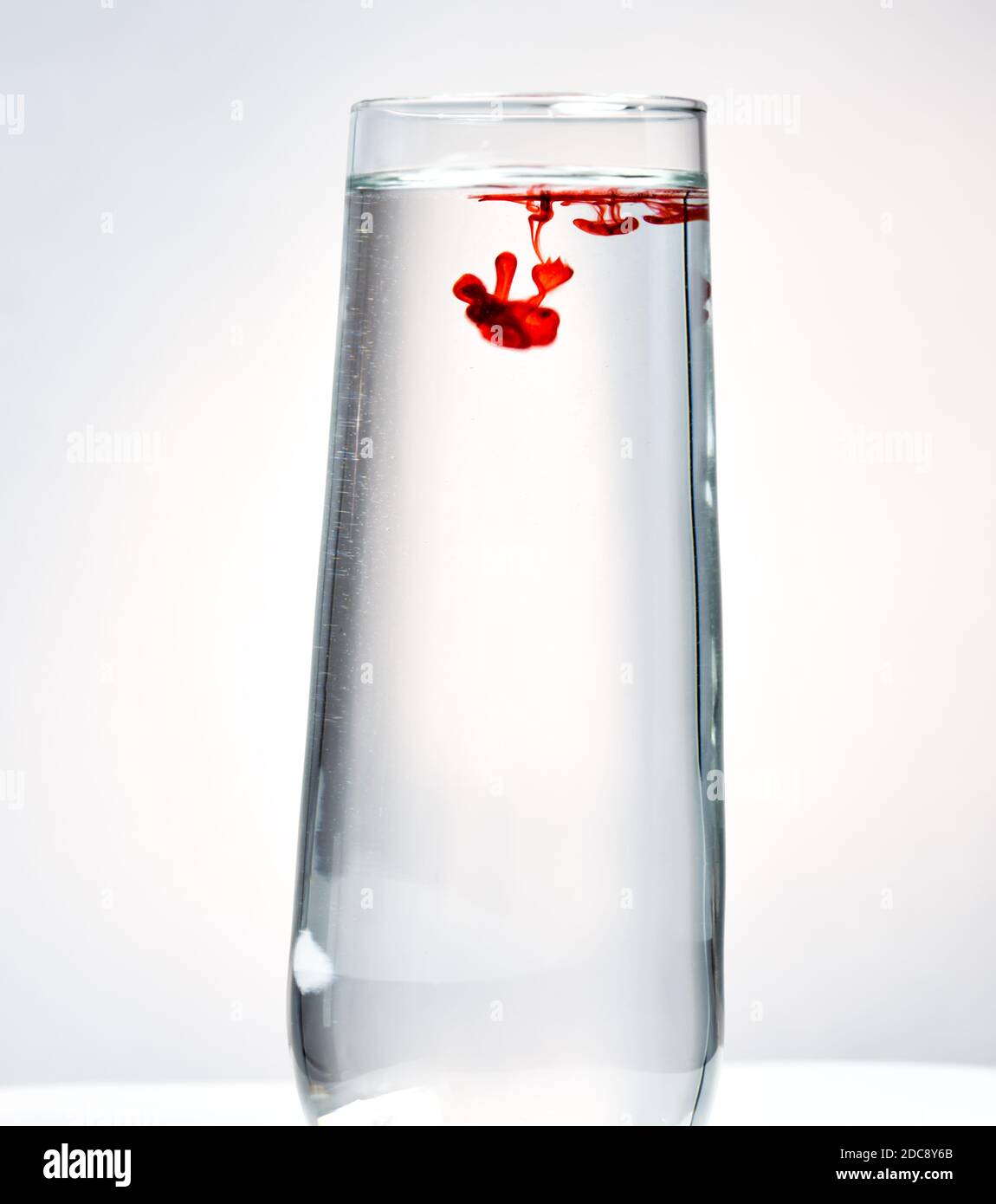 Gota de colorante de color flotando en vidrio de agua transparente Foto de stock