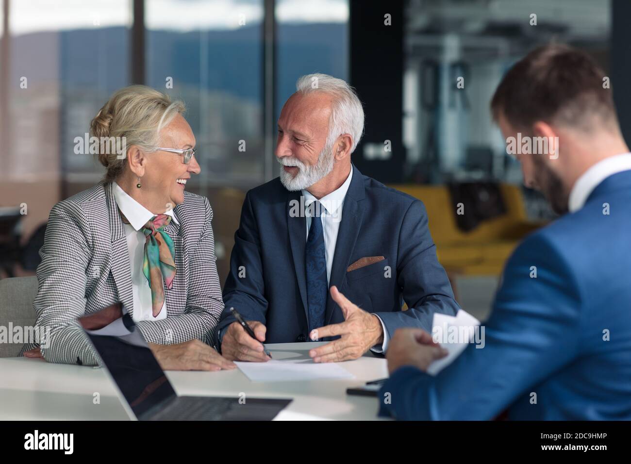 Pareja de edad positiva consultando con el agente de seguros Foto de stock