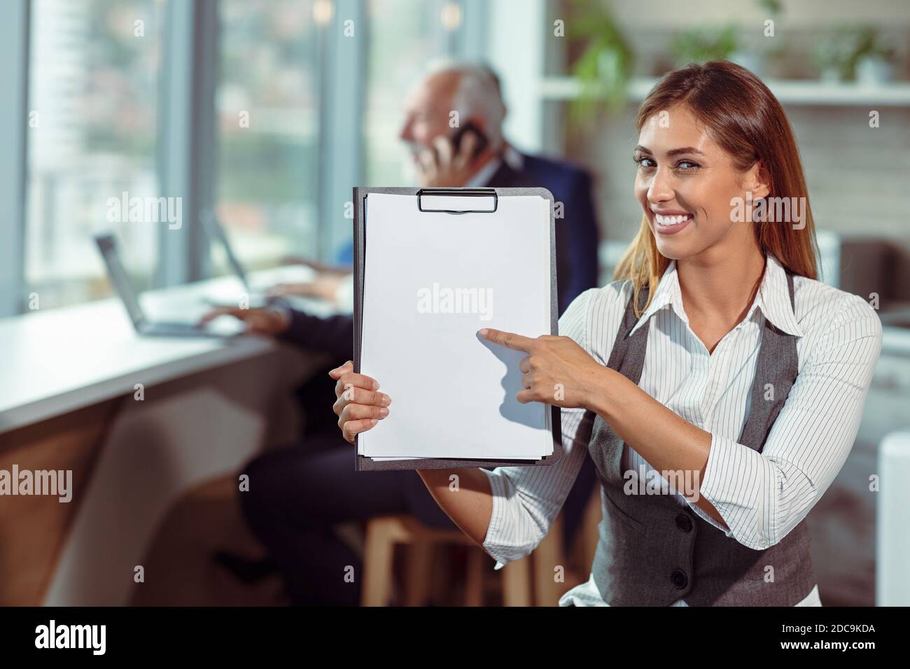 La mujer de negocios tiene papel blanco. Joven sonriendo. Foto de stock