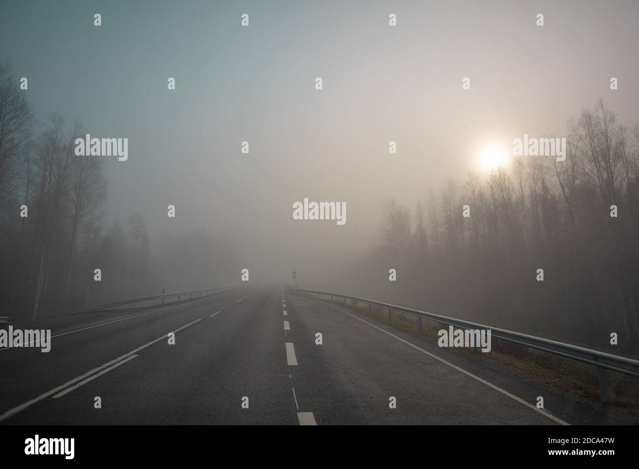Mala visibilidad. La carretera está en niebla pesada, a lo largo de los bordes de la carretera hay un bosque. Mañana de otoño en noviembre. Foto a través del parabrisas de un coche. Foto de alta calidad Foto de stock