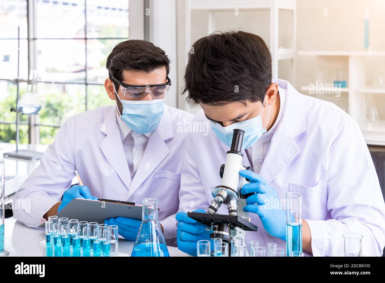 Dos científicos investigadores asiáticos y árabes varones que trabajan en  laboratorio, estudian la sustancia de riesgo biológico con equipo científico  y microscopio Fotografía de stock - Alamy