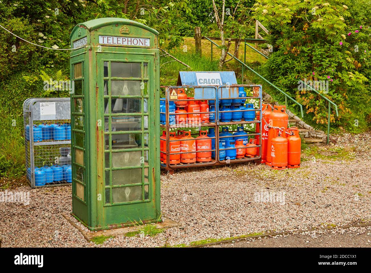 Caja de teléfono verde con bombonas de gas rojas y azules Foto de stock