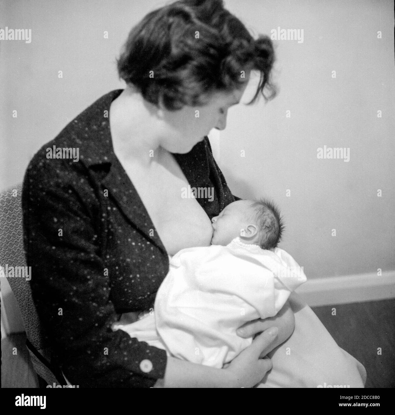 Una madre amamantó a su nuevo bebé en la década de 1950 Foto de stock