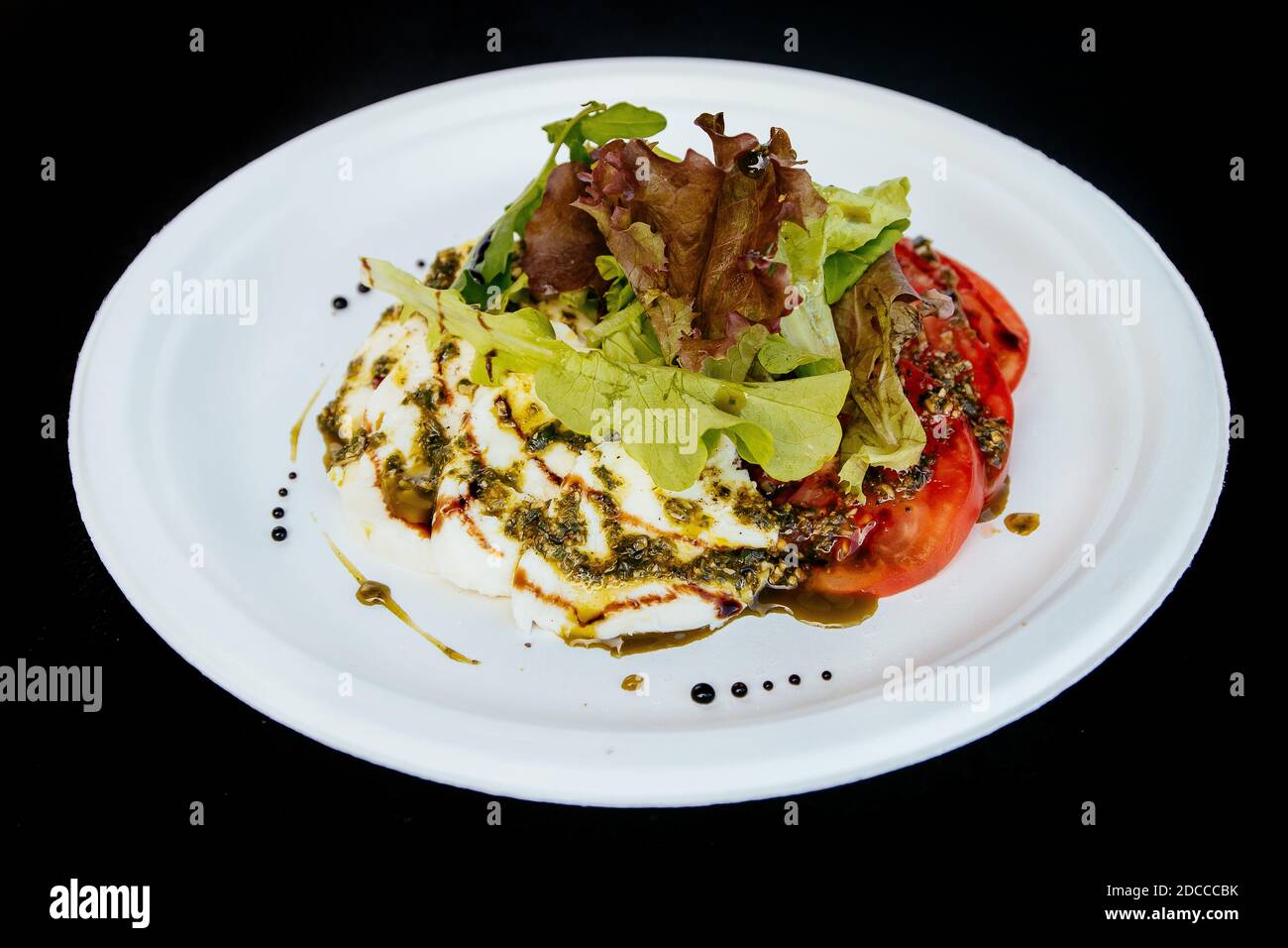 Ensalada de verduras con queso de tomate, en un plato blanco, aislar. Foto de stock