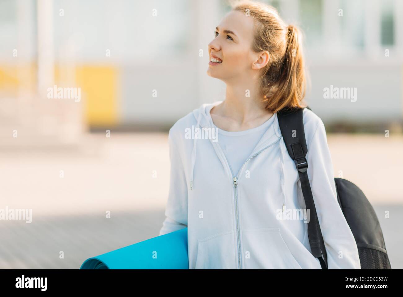 Vaya a la práctica. Mujer deportiva con un maletín y un gimnasio Mat camina  por la calle para entrenar. Deportes y un estilo de vida saludable  Fotografía de stock - Alamy