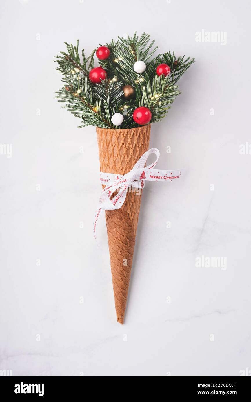 Fondo del concepto de Navidad. Ramas de abeto con decoraciones navideñas en cono helado sobre fondo blanco Foto de stock