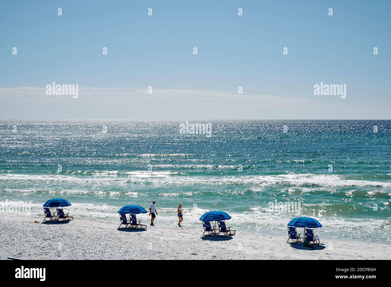 Dos personas caminando por la playa de arena blanca y las playas de la Florida Panhandle, Golfo de México, en Seaside Florida, Estados Unidos. Foto de stock