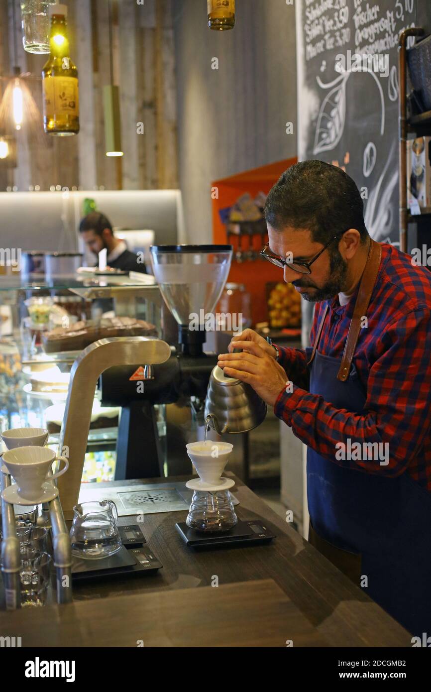 Alemania/ Frankfurt Main /Coffee Style /Barista Verrando agua en el filtro  de goteo para hacer café de filtro .Barista Verrando café a través del  filtro en el café Fotografía de stock -
