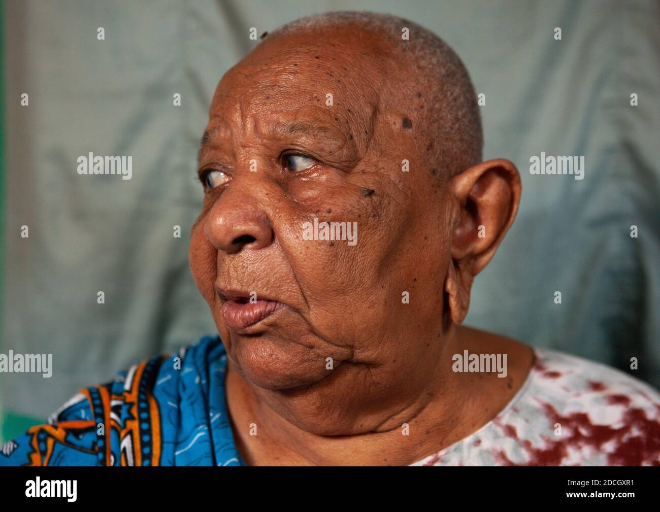 Retrato de una mujer mayor con la cabeza afeitada y los lóbulos de las orejas agrandados, condado de Lamu, Siyu, Kenia Foto de stock