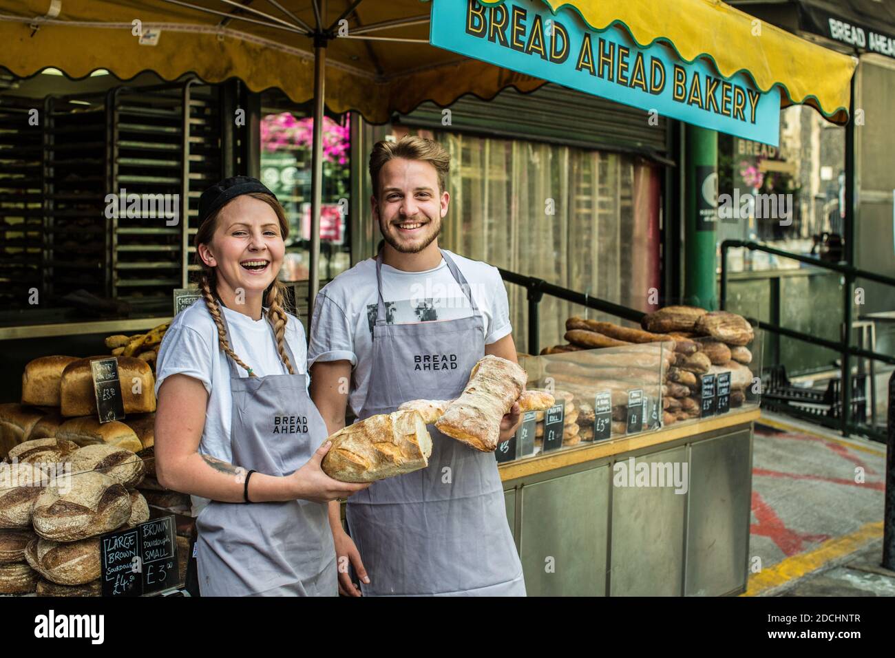 Feliz vendedor femenino y masculino en el puesto Bread Ahead en Borough Market, Southwark, South London, Foto de stock