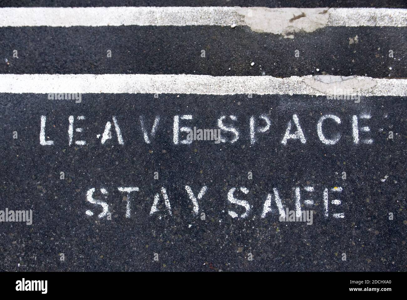 Deje espacio manténgase seguro pintado en el pavimento para promover el distanciamiento social debido a covid19. Foto de stock