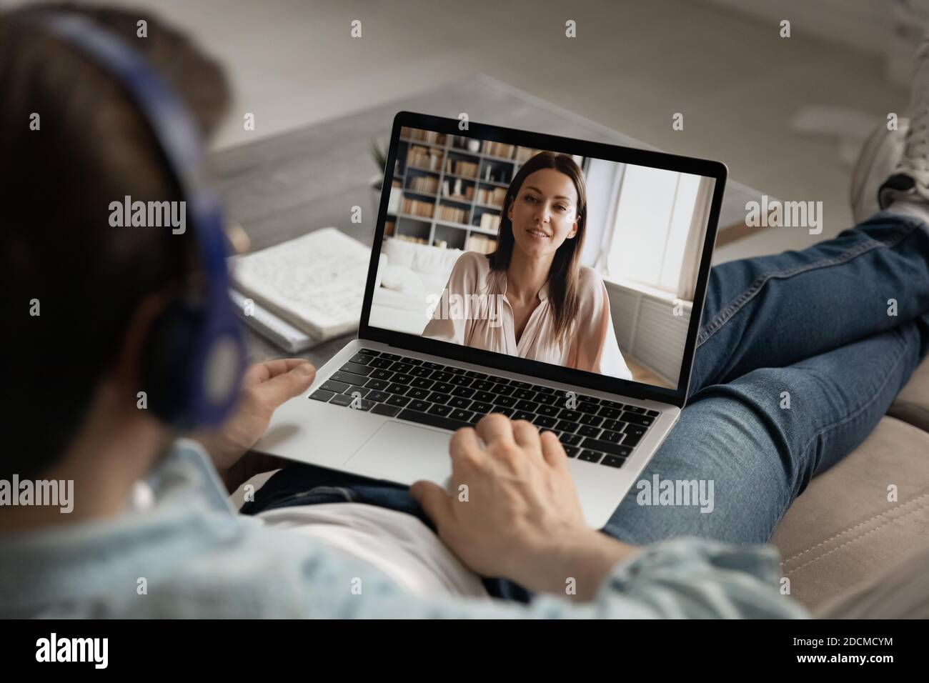 Hombre joven en auriculares con videollamada hablar con novia. Foto de stock