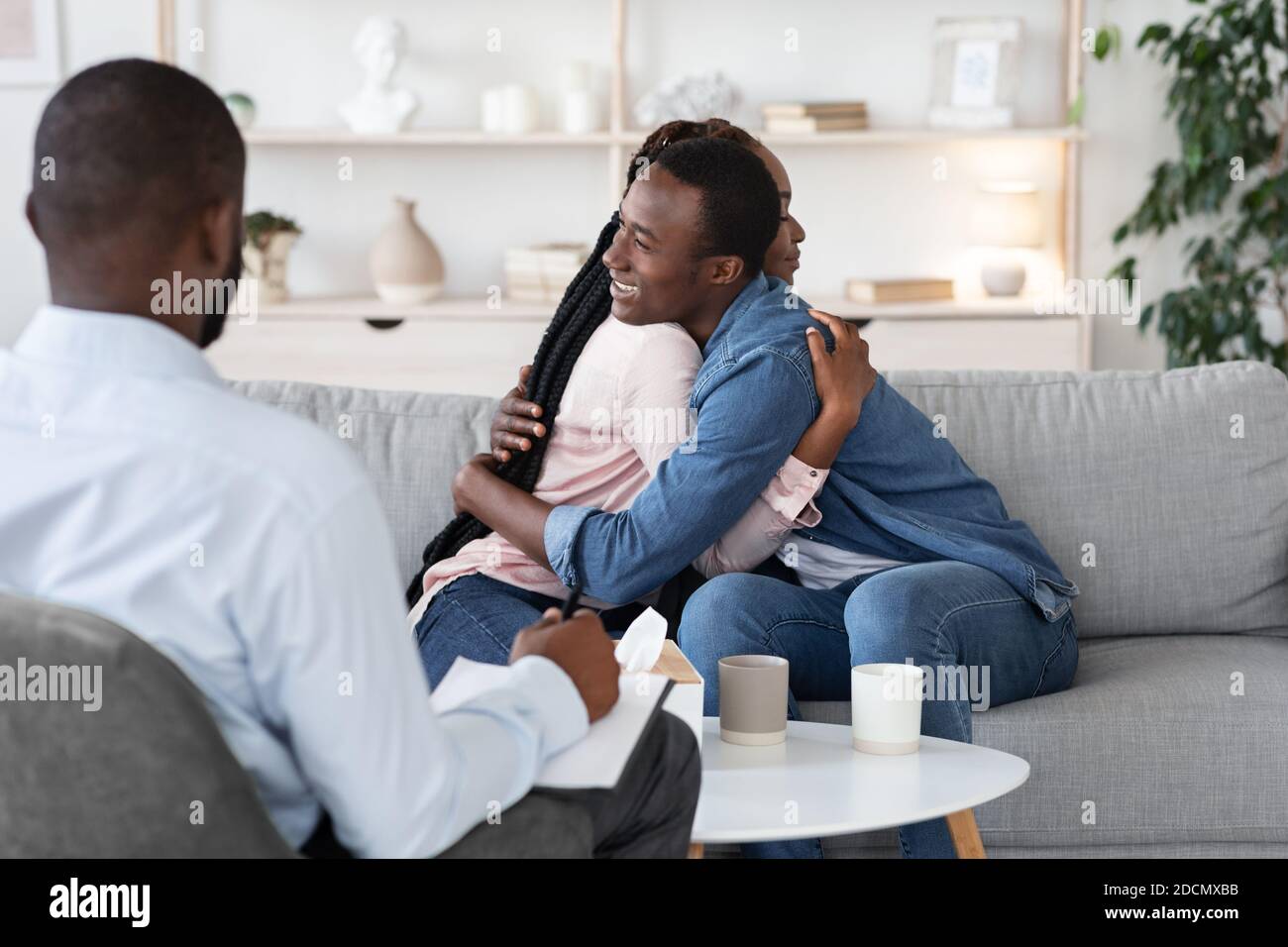 Terapia de parejas. Esposos negros felices abrazando en la oficina del consejero civil después de la reconciliación Fotografía de stock - Alamy Terapia de parejas. Esposos negros felices abrazando en la oficina del consejero civil después de la reconciliación Fotografía de stock - Alamy