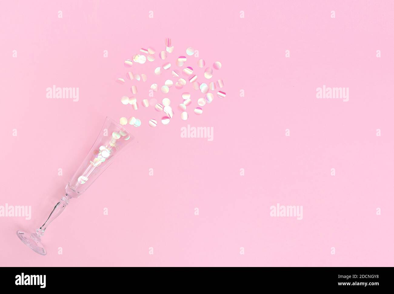 Сhampagne flauta llena de confeti rosados sobre fondo rosa. Espacio de copia, disposición plana Foto de stock