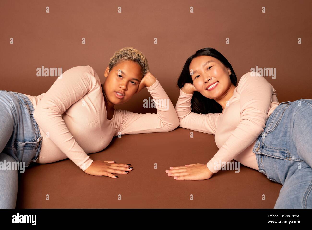 Dos jóvenes mujeres contemporáneas de diversas etnias en jeans y. amantes del pulso Foto de stock