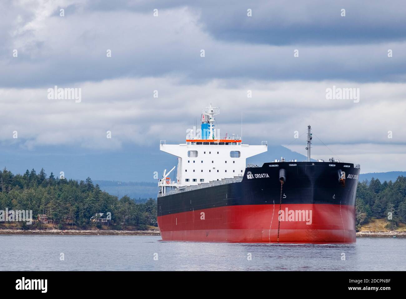 Anclado justo al lado de la isla de Thetis, BC, el carguero de 228 metros de largo 'Bulk Croatia' se eleva sobre la costa, desatando la ira y la controversia local. Foto de stock