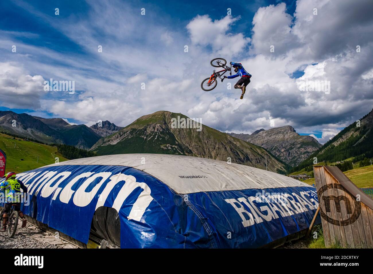 Un ciclista de descenso está practicando un salto difícil con la seguridad de aterrizar en un gran airbag en el Mottolino Bike Park, que rodea las montañas de Livi Foto de stock