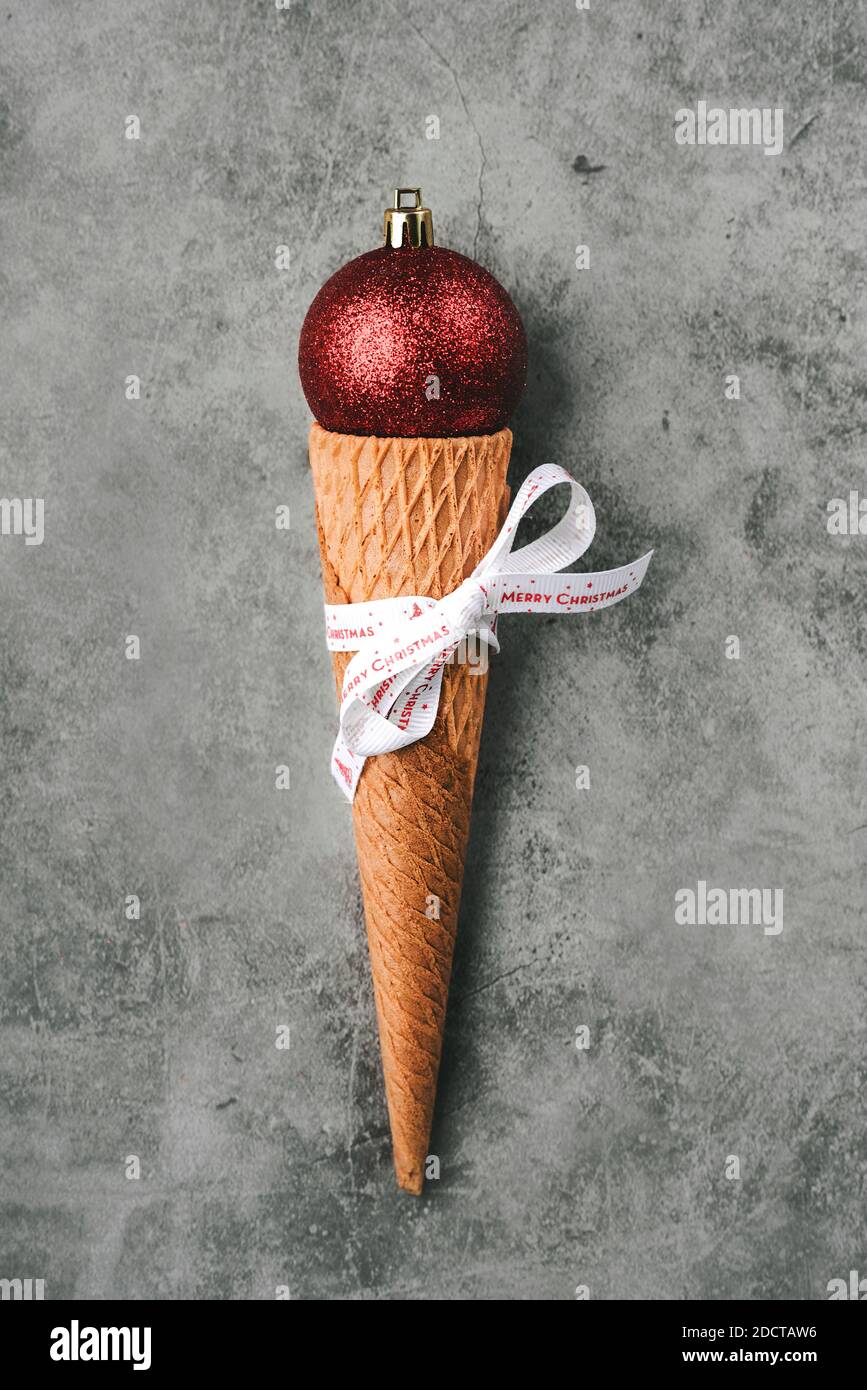Fondo del concepto de Navidad. Bola roja de Navidad en cono helado sobre fondo gris Foto de stock