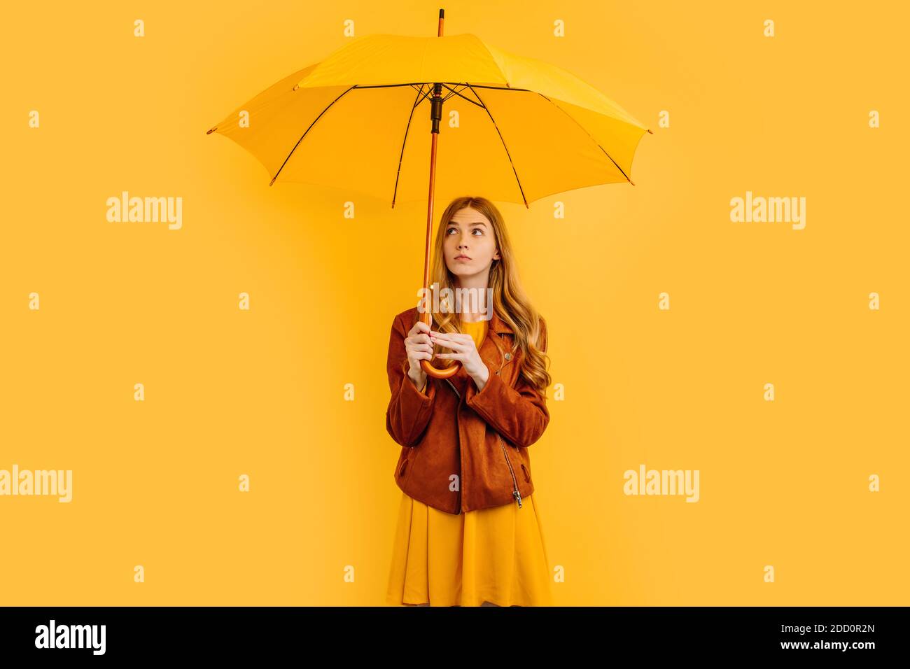 Hermosa chica con un paraguas amarillo, con una cara pensativa Fotografía  de stock - Alamy