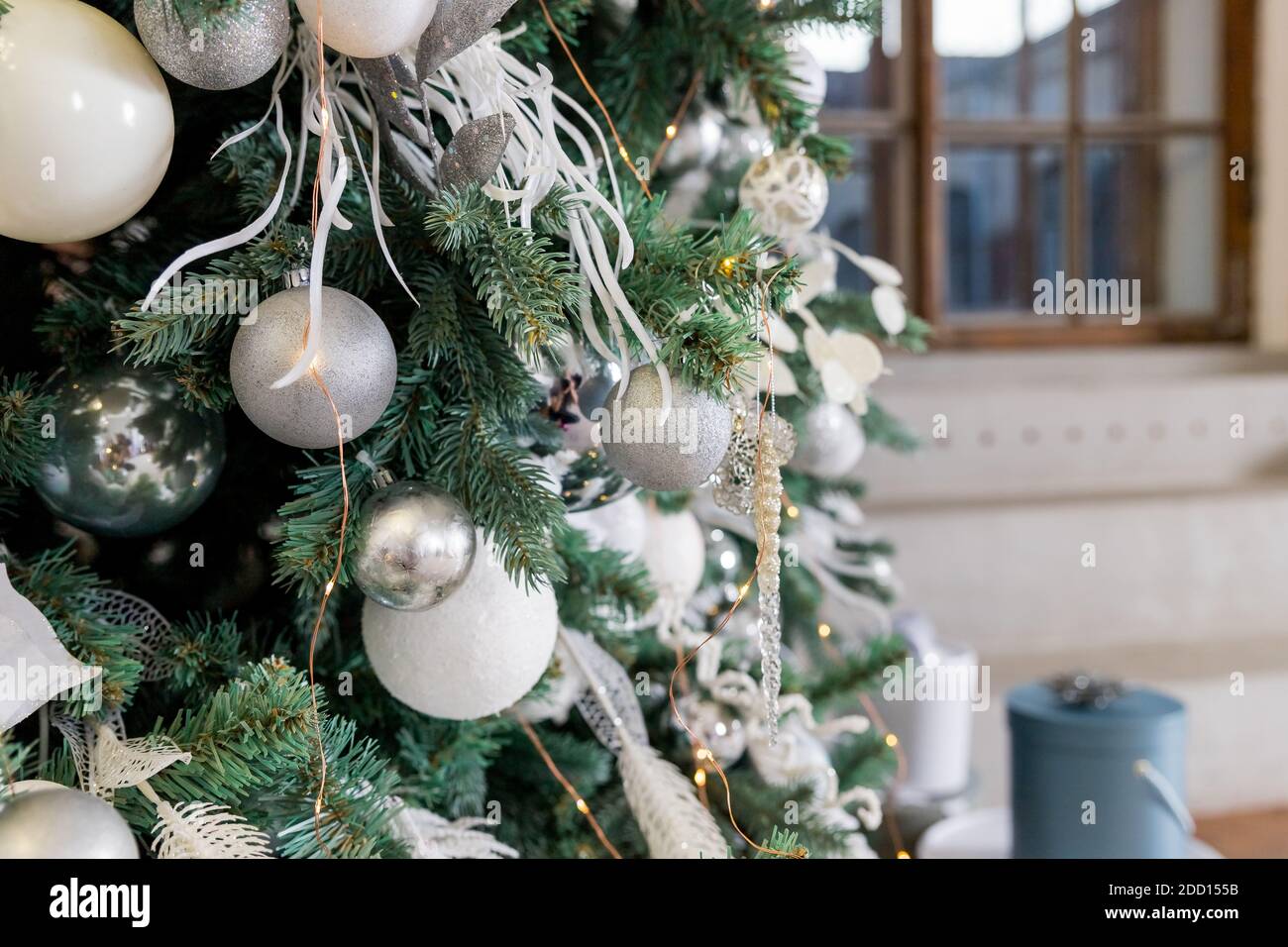 Rama de árbol de Navidad decorada con bolas de plata y decoración blanca.  Árbol con estilo con bolas de plata y luces en la sala de fiestas.  Decoración moderna Fotografía de stock -