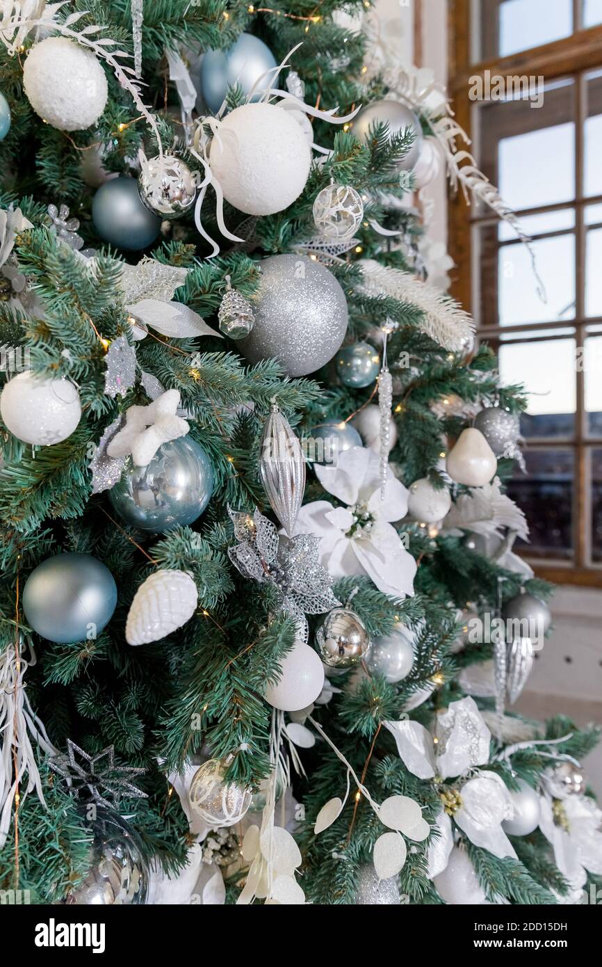 Rama de árbol de Navidad decorada con bolas de plata y decoración blanca.  Árbol con estilo con bolas de plata y luces en la sala de fiestas.  Decoración moderna Fotografía de stock -