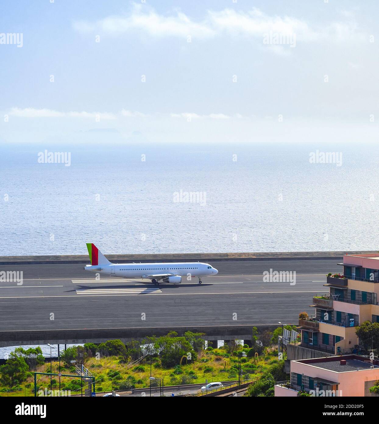 Avión en la pista del aeropuerto de Funchal junto al océano Atlántico, bloques de apartamentos en primer plano. Madeira, Portugal Foto de stock