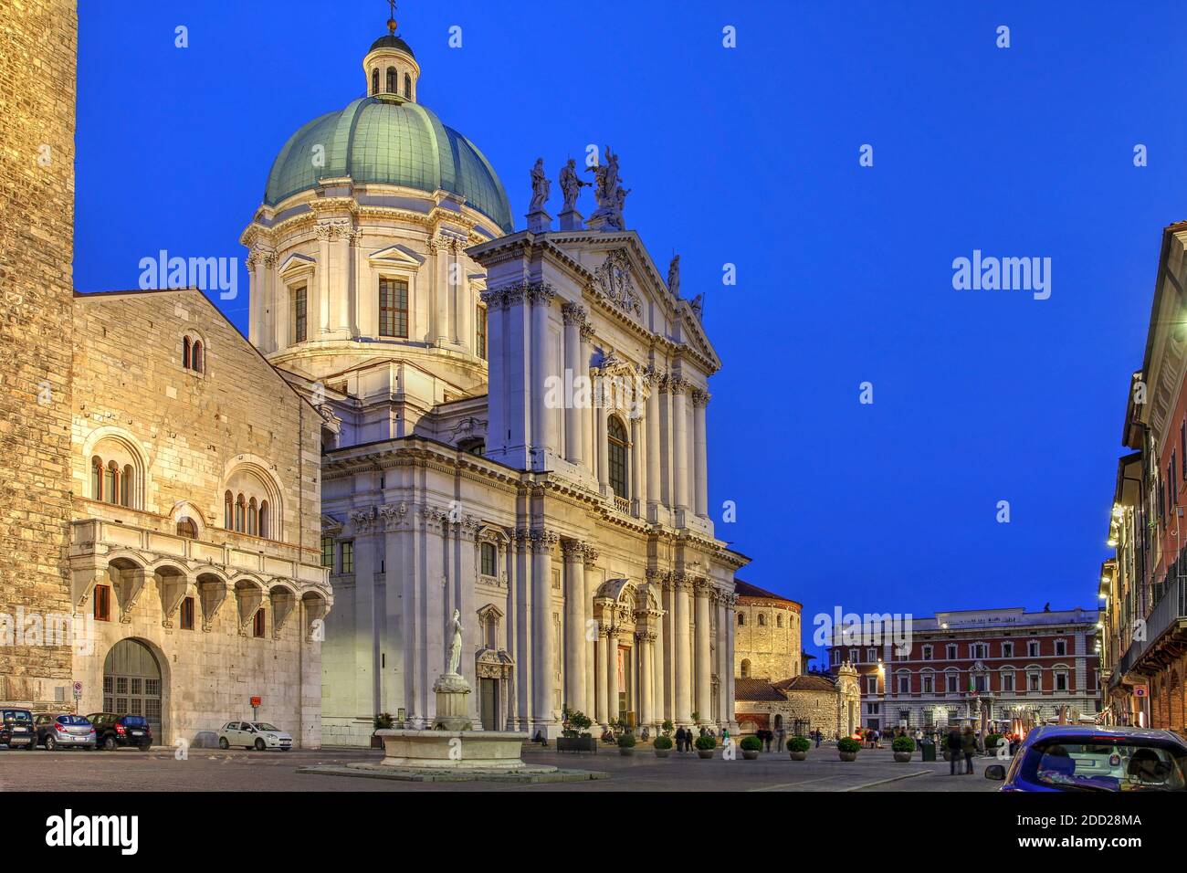 Escena nocturna en la Piazza Paolo VI, con el Palacio Broletto (Ayuntamiento), el Duomo Nuovo (Nueva Catedral) y el Duomo Vecchio (Antigua Catedral o la Rotonda) Foto de stock