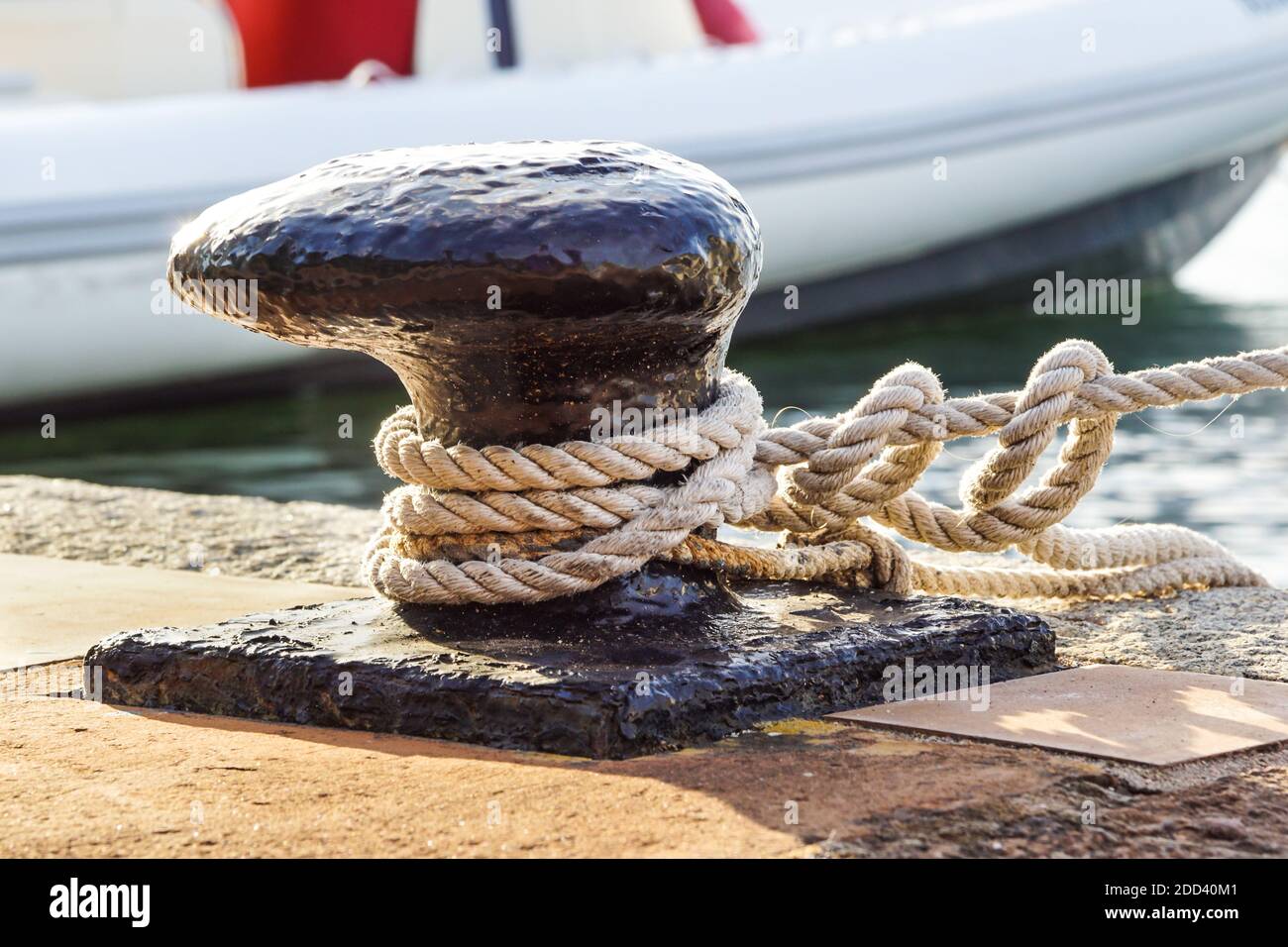 Cuerda de amarre y bollard sobre el agua de mar y yates de fondo. Foto de stock