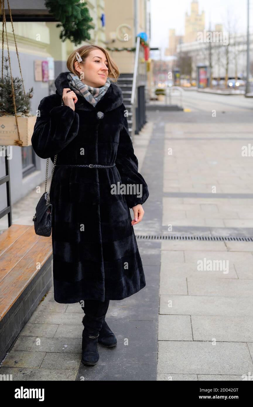 una joven mujer en un moderno abrigo de piel de invierno camina por una calle la ciudad Fotografía de stock - Alamy