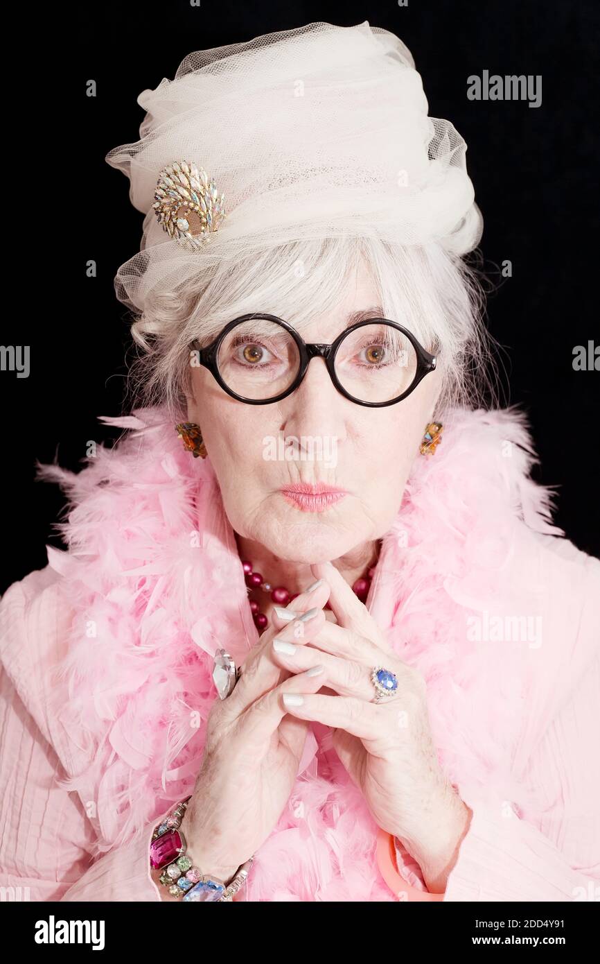 Un retrato de una hermosa mujer mayor con sentido de la moda que nadie debe desafiar! Sombrero vintage rosa con broach, boa rosa y muchas joyas adornan esto Foto de stock