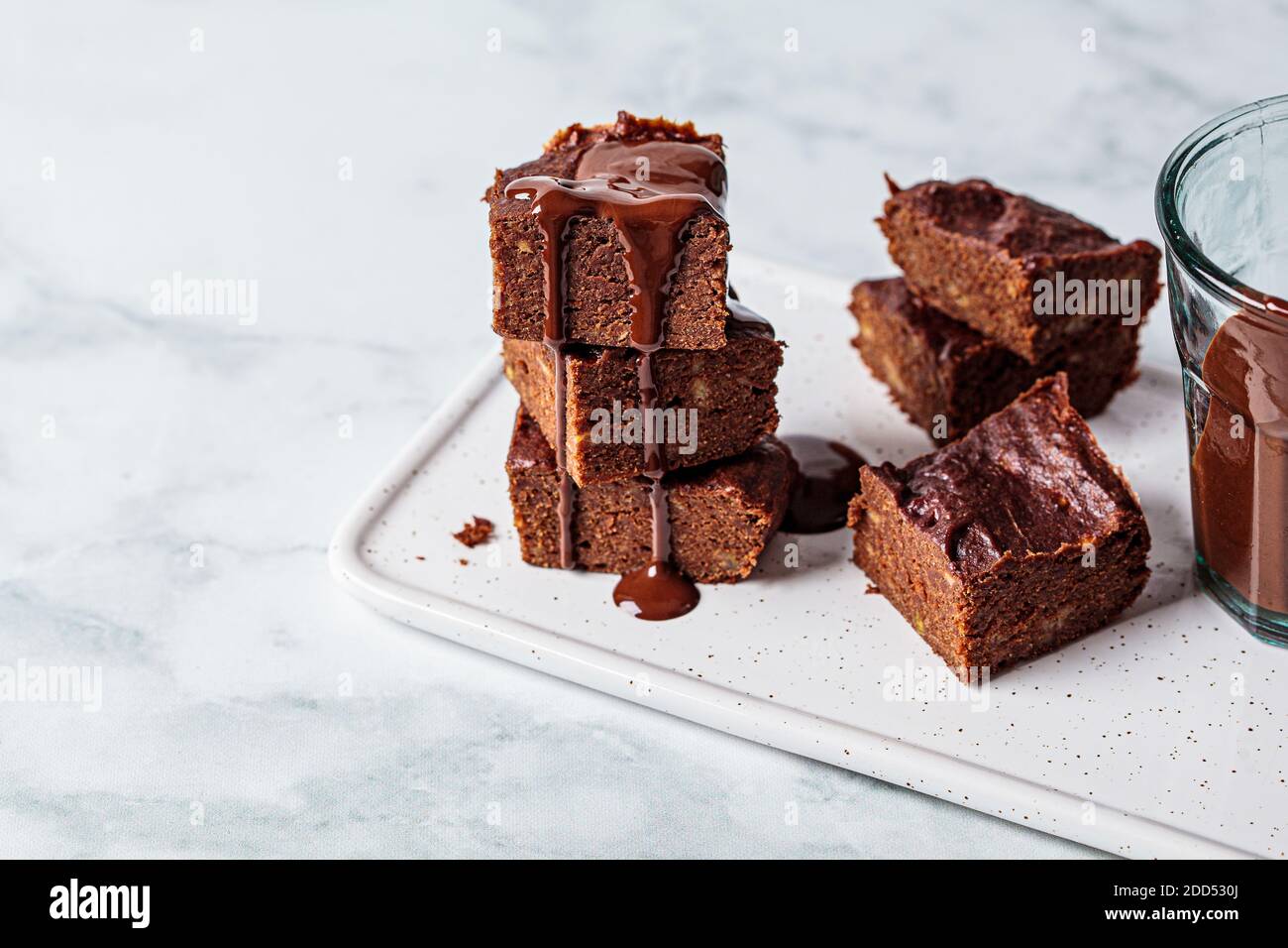 Pila de brownies veganos con chocolate negro sobre un tablero blanco, fondo  blanco. Concepto de postre vegano Fotografía de stock - Alamy