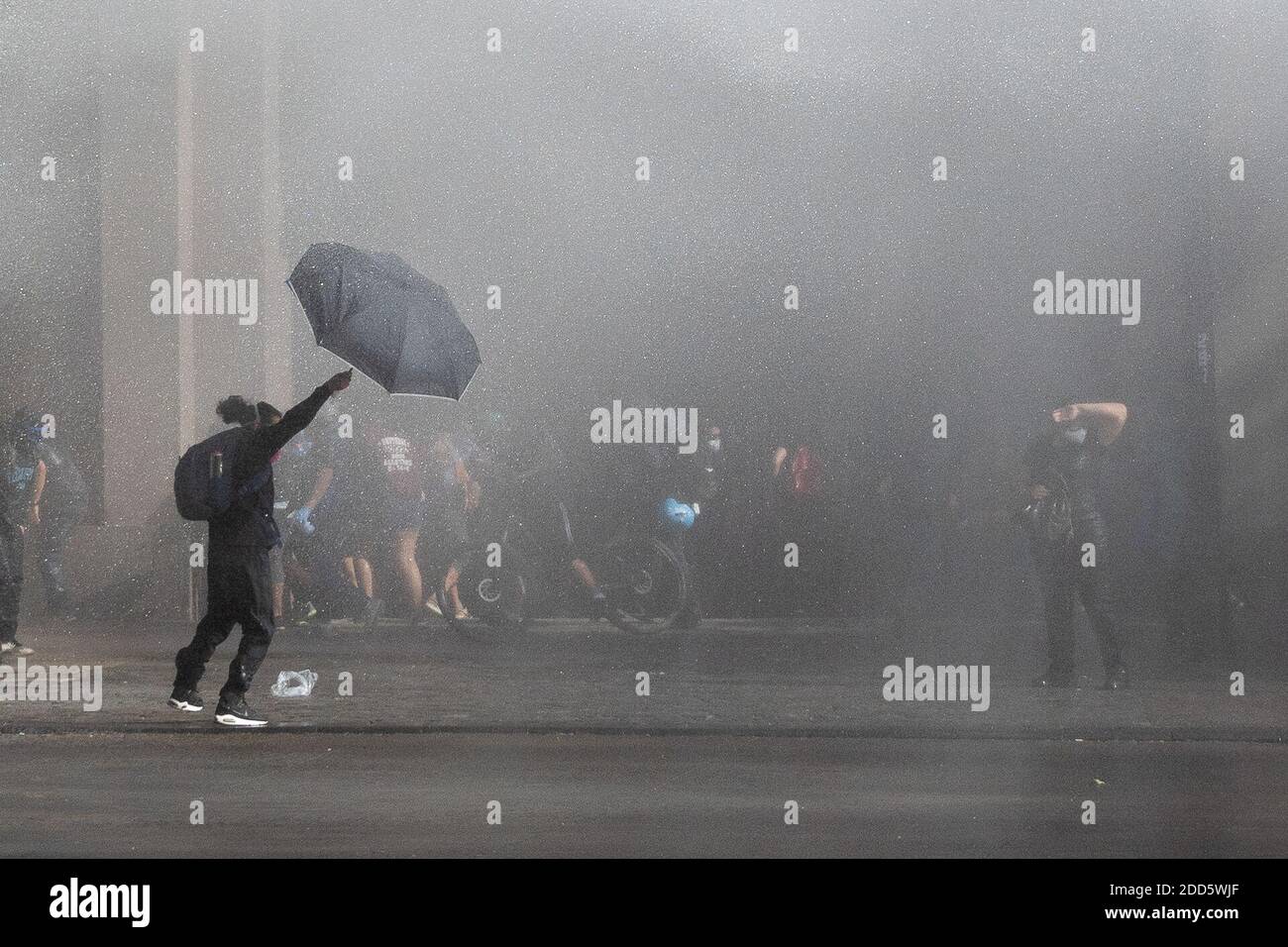 Santiago, Metropolitana, Chile. 23 de noviembre de 2020. Un manifestante se  cubre con un paraguas del agua arrojada por la policía, en medio de  protestas contra el gobierno de Sebastián Piñera. Crédito: