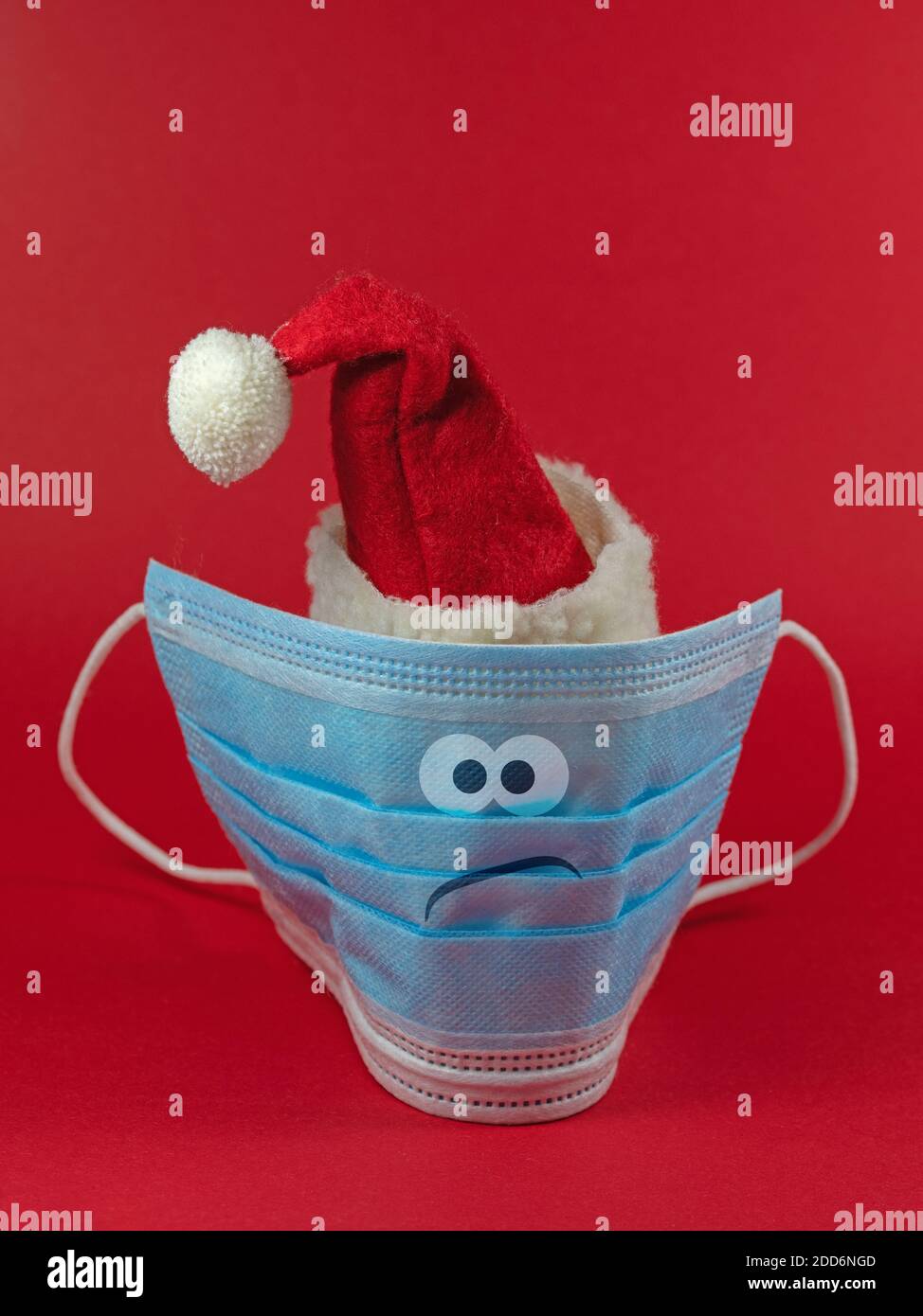 Mascarilla facial con sombrero de Santa Claus y cara en un mal humor Foto de stock