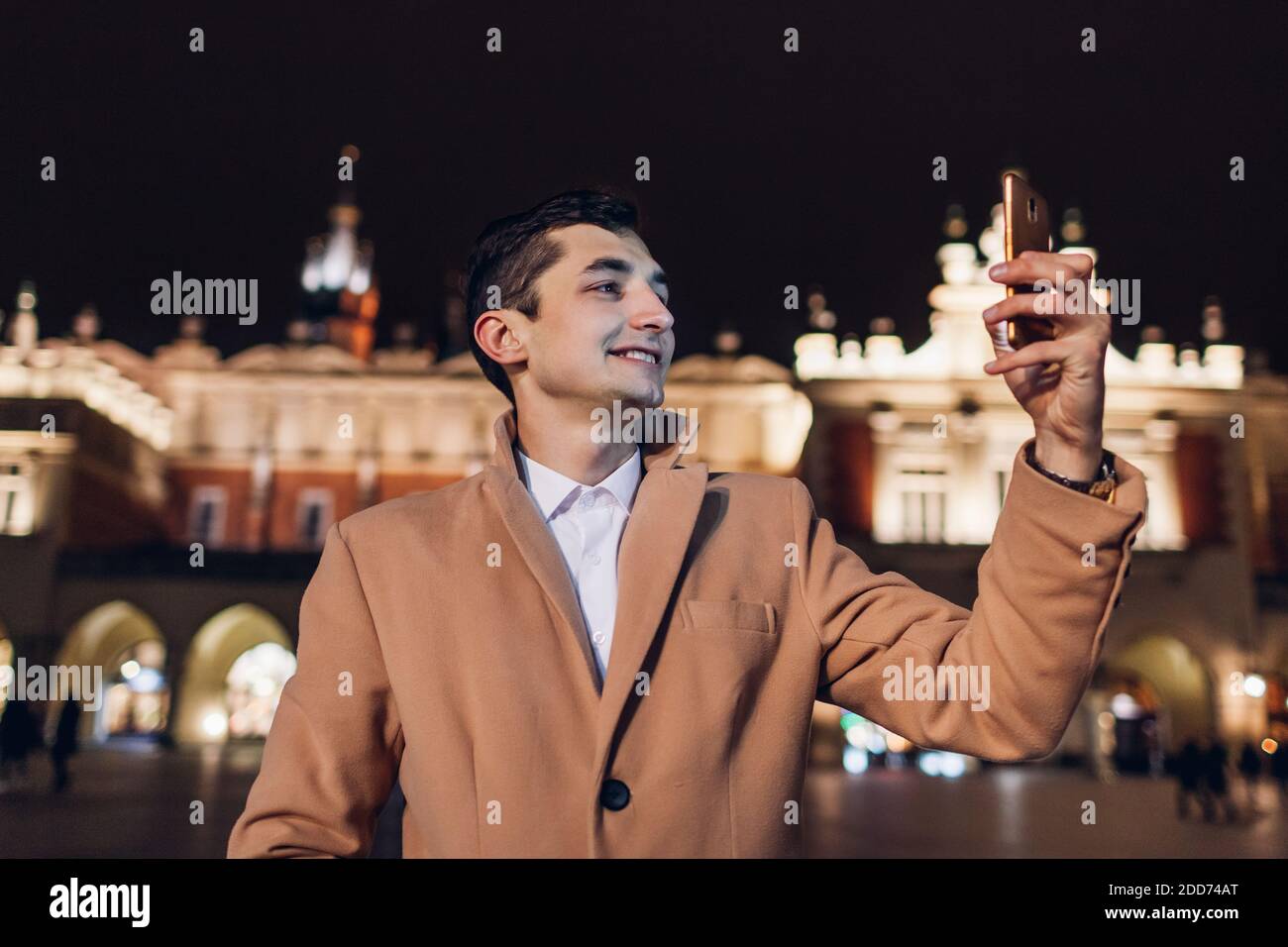 Turista tomando selfie en el teléfono inteligente por la noche en la plaza del mercado en Cracovia Polonia. Viajar por Europa Foto de stock