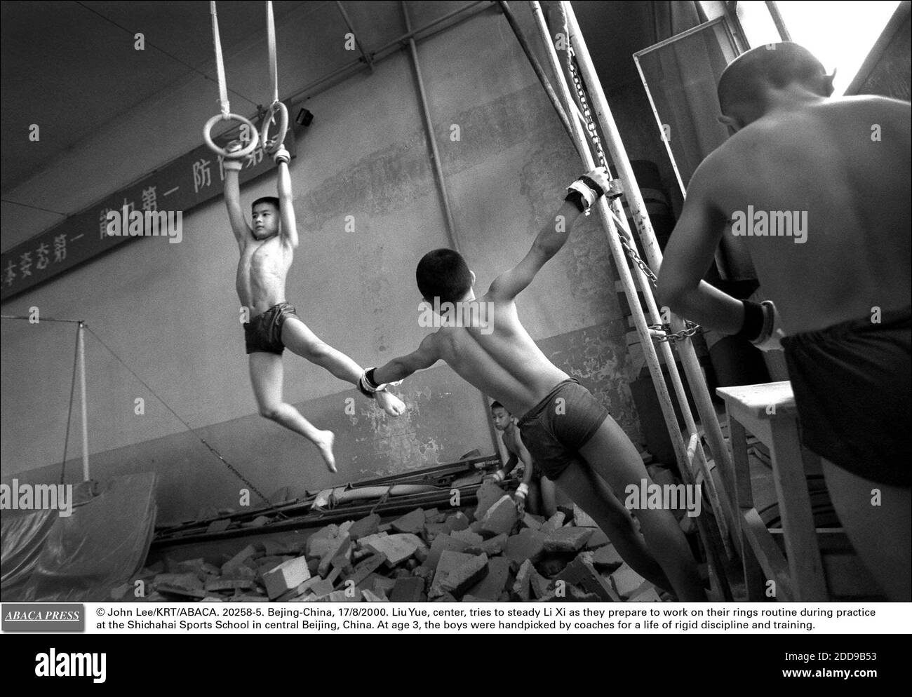 NO HAY CINE, NO HAY VIDEO, NO HAY TELEVISIÓN, NO HAY DOCUMENTAL - © JOHN LEE/KRT/ABACA. 20258-5. Pekín-China, 17/8/2000. Liu Yue, centro, trata de estabilizar a Li Xi mientras se preparan para trabajar en su rutina de anillos durante la práctica en la Escuela de Deportes Shichahai en el centro de Beijing, China. A la edad de 3 años, los chicos fueron seleccionados a mano por c Foto de stock