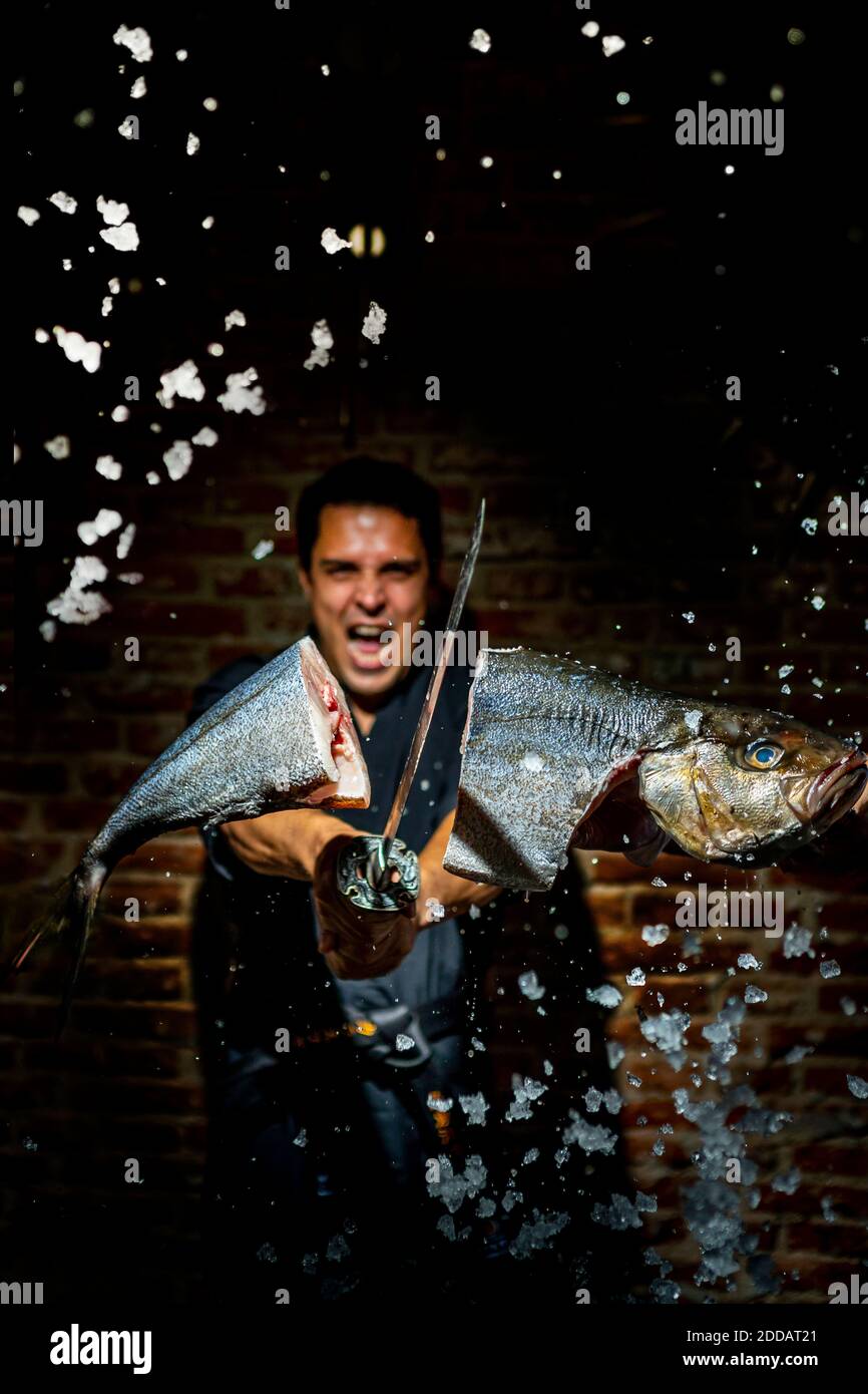 El hombre cortando pescado con espada mientras está de pie en la cocina comercial Foto de stock