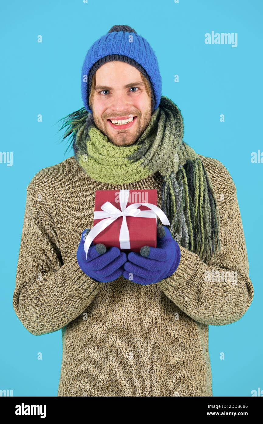 El hombre barbado guapo hat bufanda guantes de invierno desgaste mantenga  caja de regalo. Hipster mantenga su regalo de navidad con arco. Concepto  actual de vacaciones. Vacaciones de invierno. Dar don contagiar
