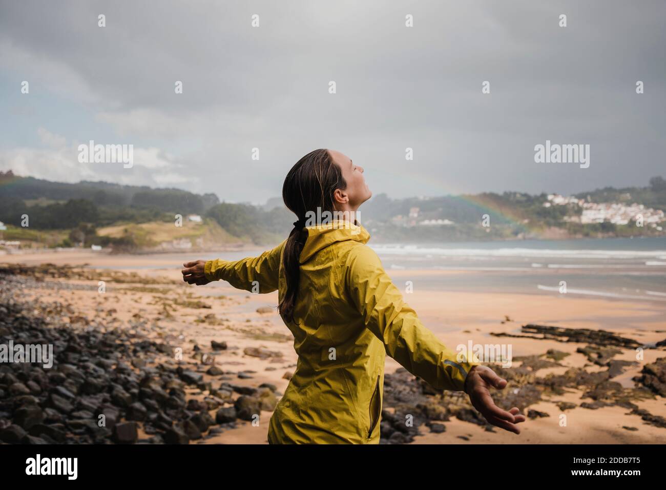 Mujer sonriente en impermeable en la playa durante la temporada de lluvias Foto de stock