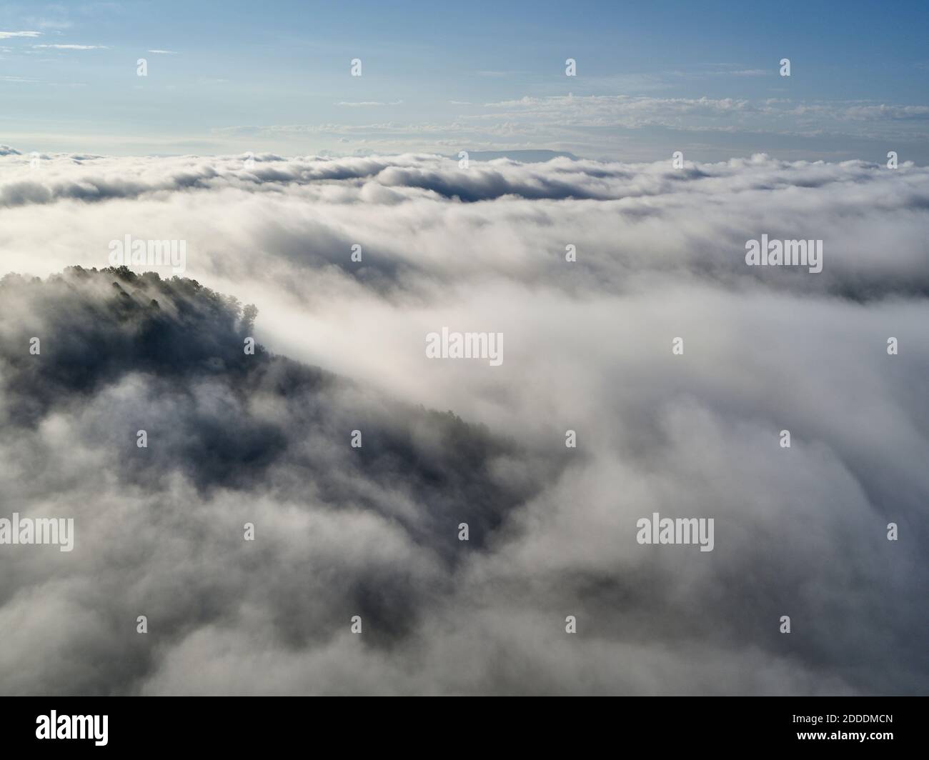 Vista aérea de las nubes bajas que rodean colinas boscosas Foto de stock