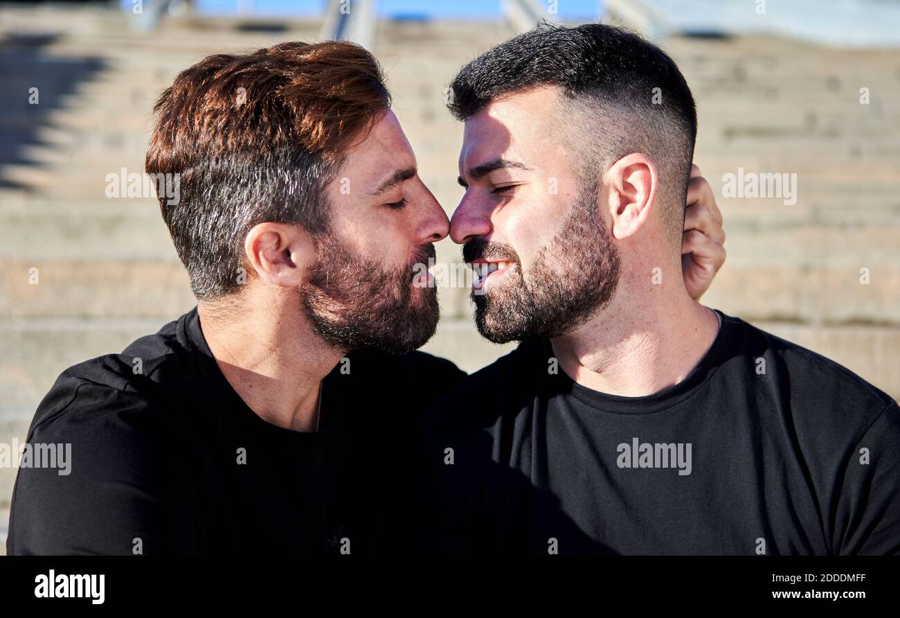Pareja homosexual romántica besando al aire libre durante el día soleado Foto de stock