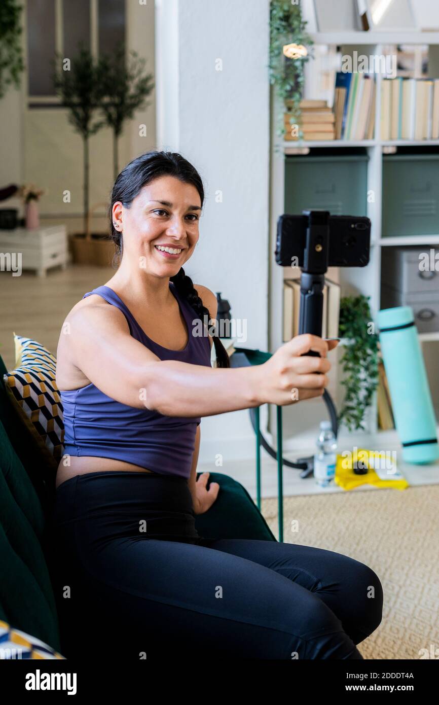 Mujer atleta grabación de vídeo en la cámara mientras está sentado en casa Foto de stock