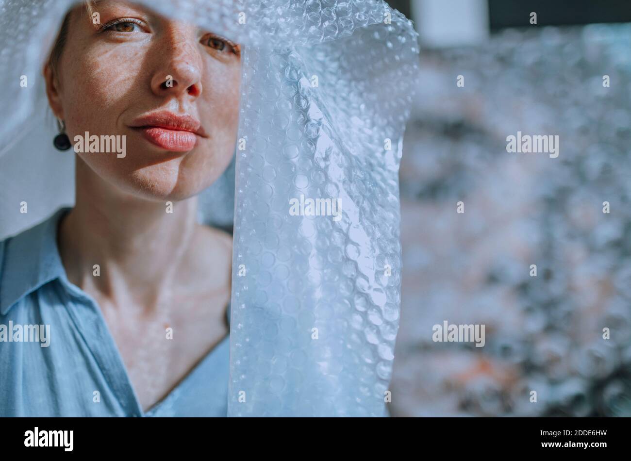 Mujer artista cubierta en envoltura de burbujas en el estudio de arte Foto de stock