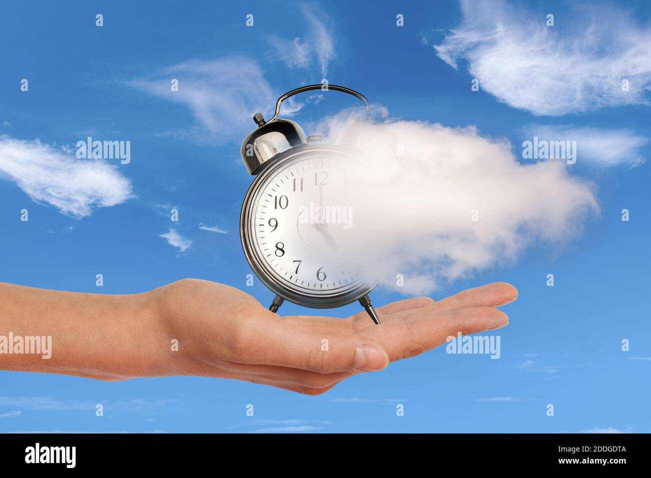 Mano sosteniendo un reloj disolviendo en una nube. El tiempo vuela, el concepto de gestión del tiempo. Collage surrealista. Foto de stock