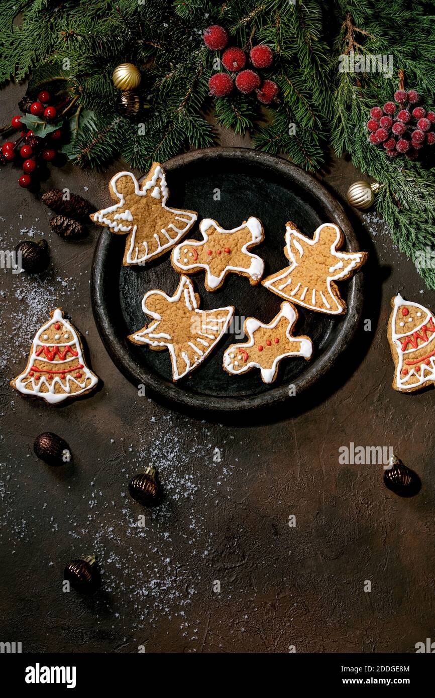 Galletas de jengibre de Navidad con guinda ornamentada. Adornos navideños, fondo oscuro. Vista superior Foto de stock