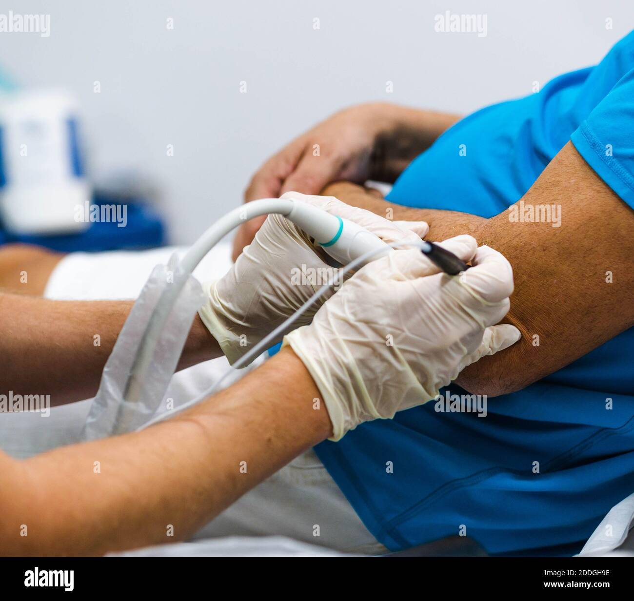 Médico de corte irreconocible en guantes de látex insertar la aguja y el  uso sonda láser para curar el codo del paciente de cultivo durante la  fisioterapia sesión en mod Fotografía de