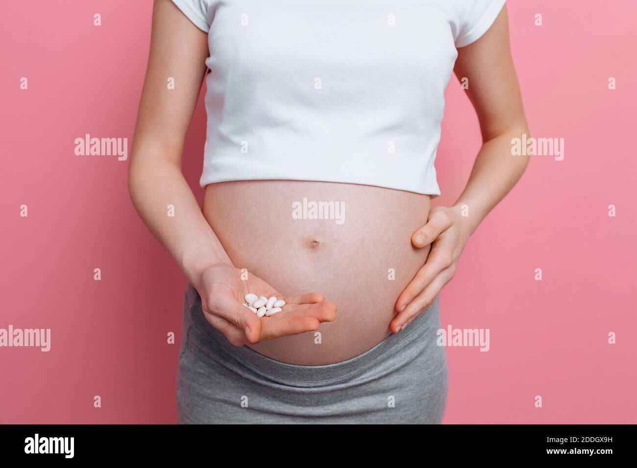 Vientre de una mujer embarazada que sostiene una mano bajo el