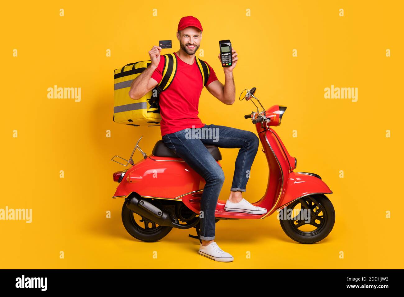 Foto de hombre viaje scooter mantener terminal tarjeta de crédito desgaste  bolsa camiseta roja casquillo aislado color amarillo fondo Fotografía de  stock - Alamy