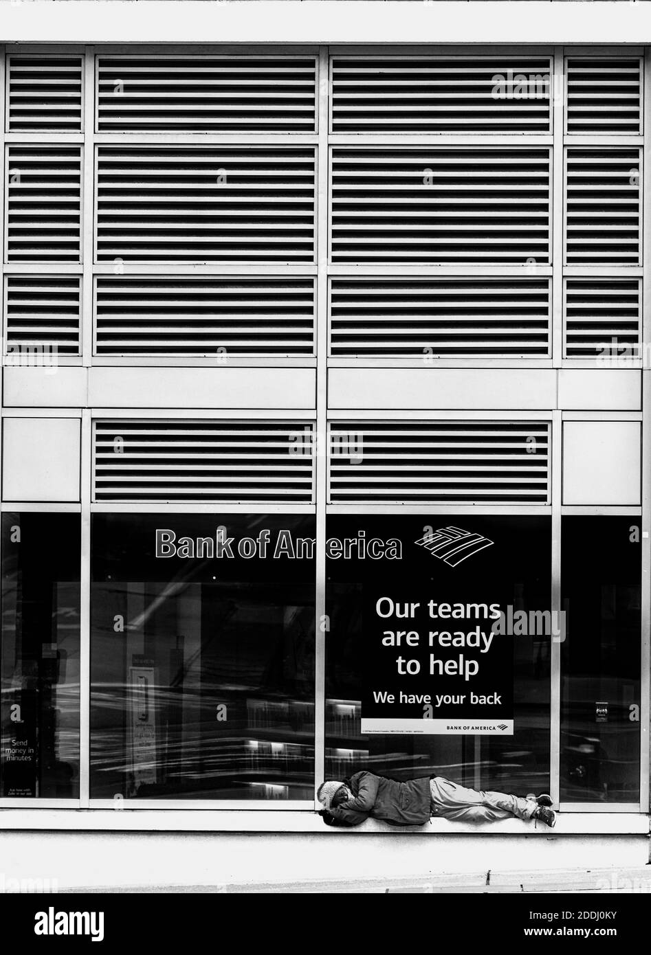WA17749-00-BW...WASHINGTON - Mujer sin hogar duerme en una estantería frente a Bank America en Seattle. Foto de stock