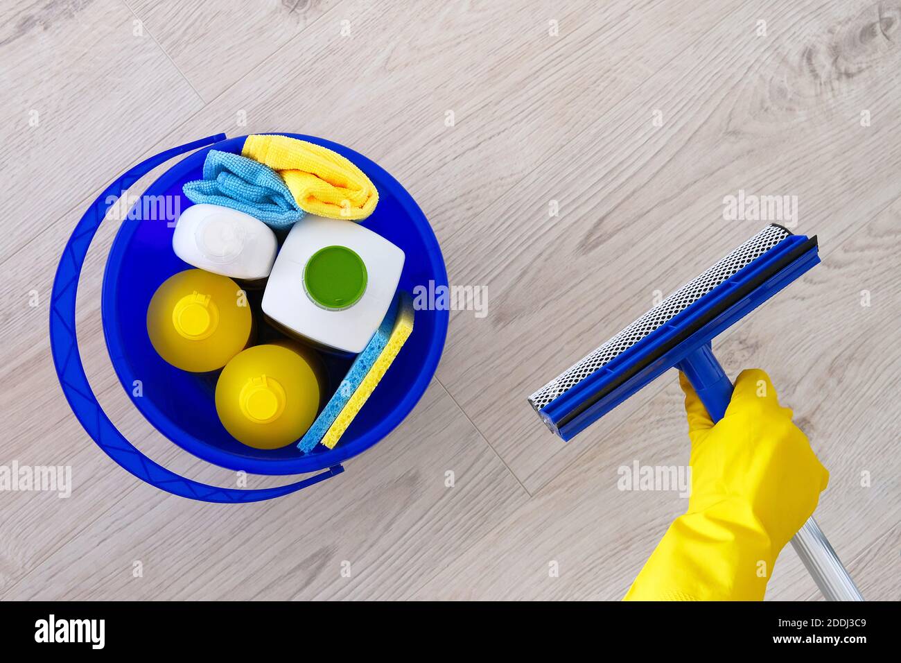 Detergentes en botellas de plástico, esponjas en balde azul para el hogar. Mopa para lavar las ventanas en la mano en guantes de goma amarilla Сleaning accesorios. Lay plano Foto de stock
