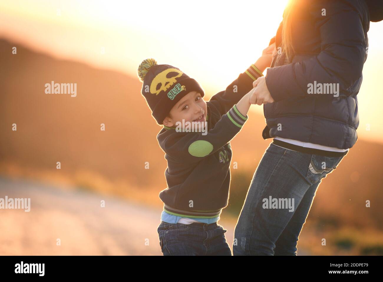 Feliz familia: Madre, hijo jugando en la naturaleza al atardecer Foto de stock